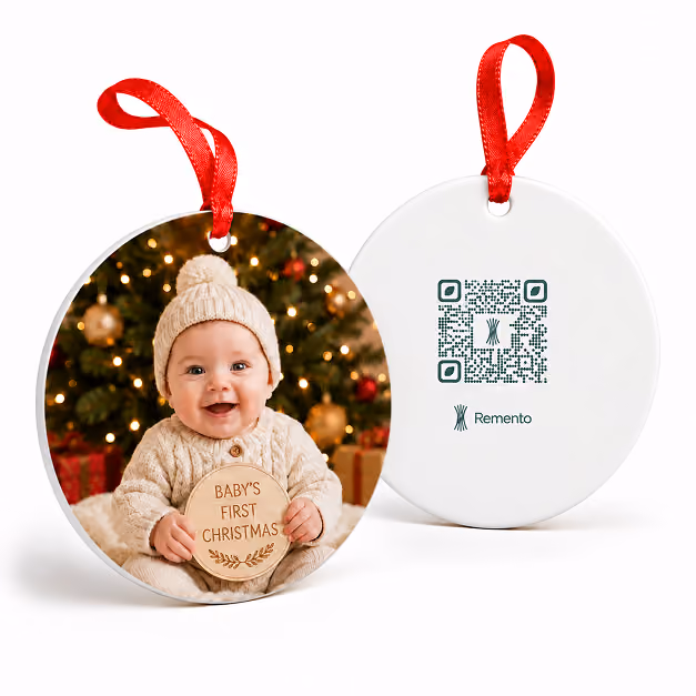 Baby's First Christmas photo ornament of a baby by a tree, shown with its QR code back