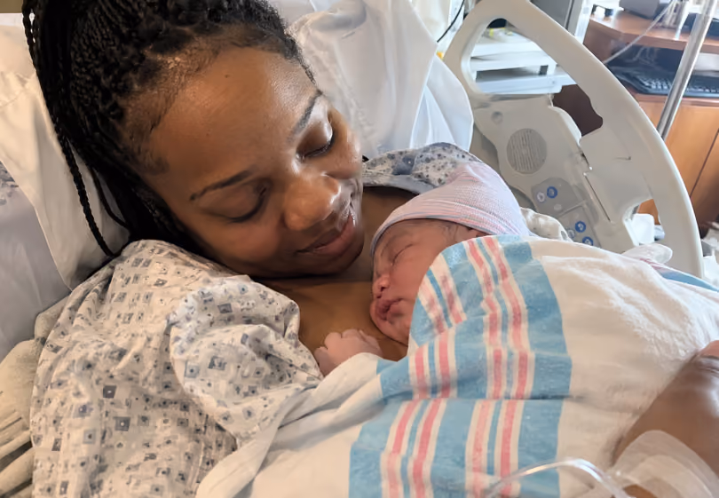Mother holding her newborn baby skin to skin in a hospital bed
