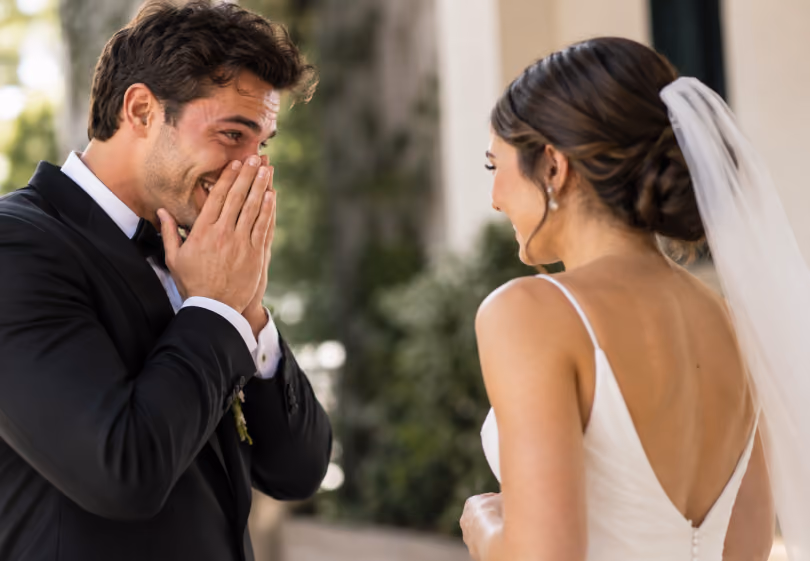 Emotional groom covering his face as he sees his bride for the first look