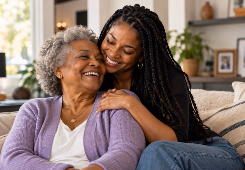 Adult daughter hugging her smiling mother on the couch
